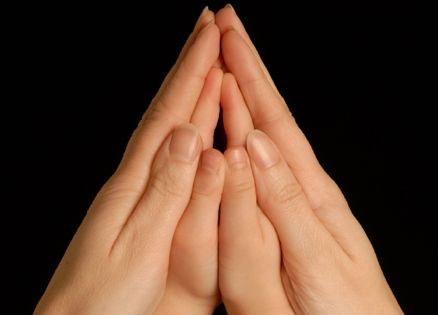 The hands of a mother and child together in prayer