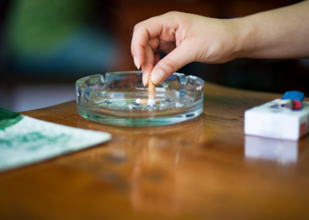 woman putting out a cigarette in an ash tray.