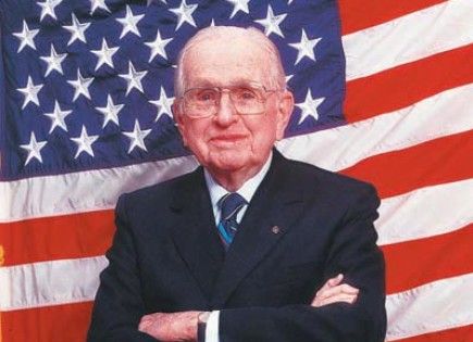 Norman Vincent Peale standing in front the US flag.