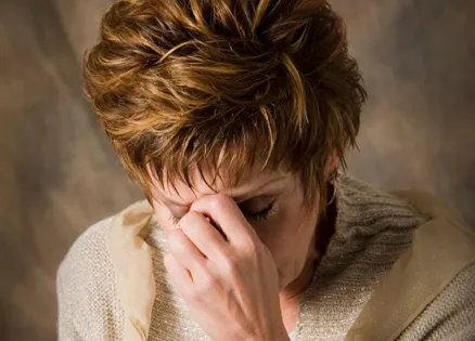 A fearful woman bows her head in prayer