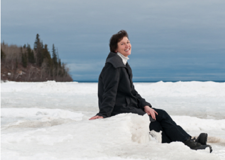 Happy woman sitting outside in the snow.