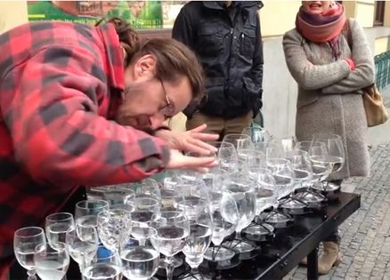 A street musician plays a tune on water-filled goblets.