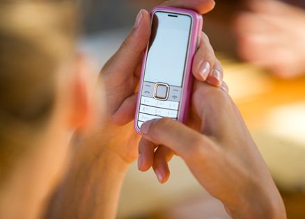 A woman prepares to make a phone call on her pink cell phone.