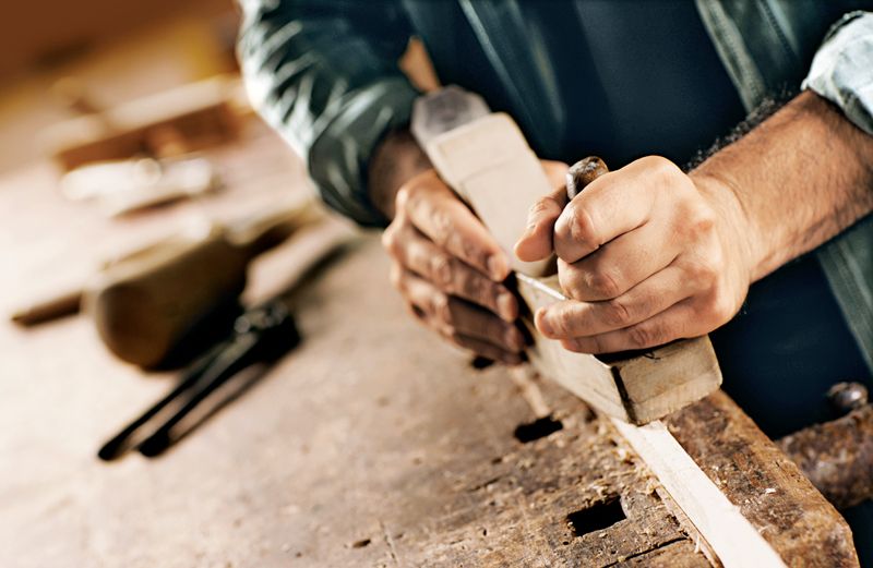 A man's hands working with wood on a workbench