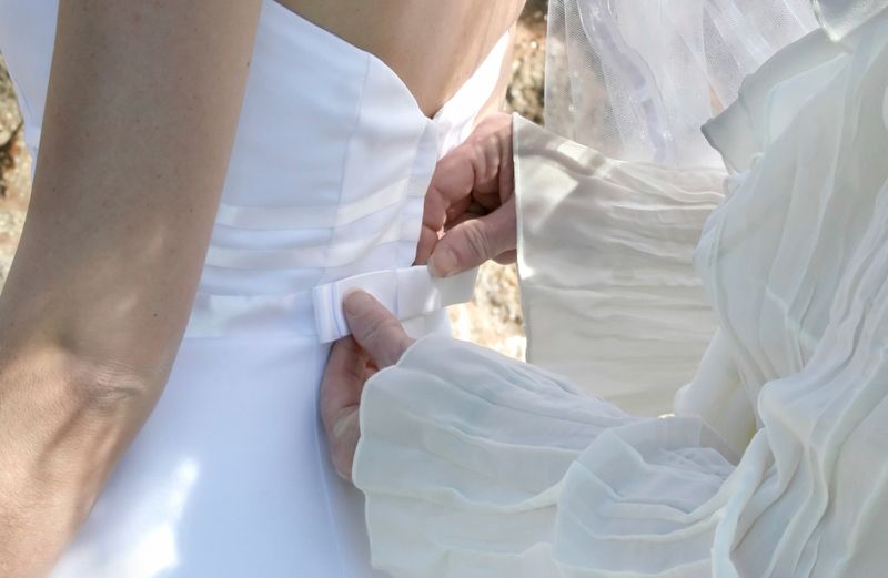 A mother adjusts her daughter's wedding dress.