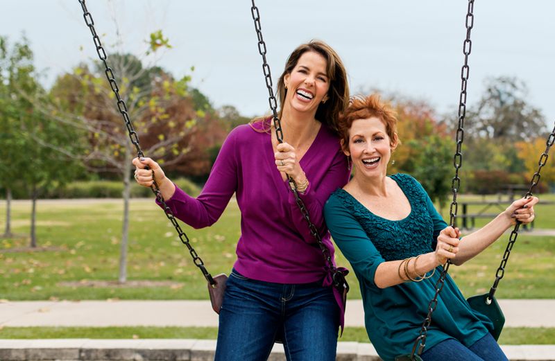 Jana (left) and Allyson have a laugh while perched in playground swings.