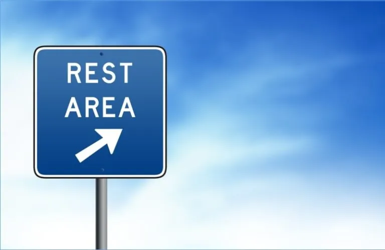 Rest area road sign against a blue sky.