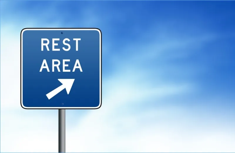 Rest area road sign against a blue sky.