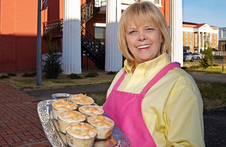 A smiling Adrian Drinkard holds a tray of small banana puddings.