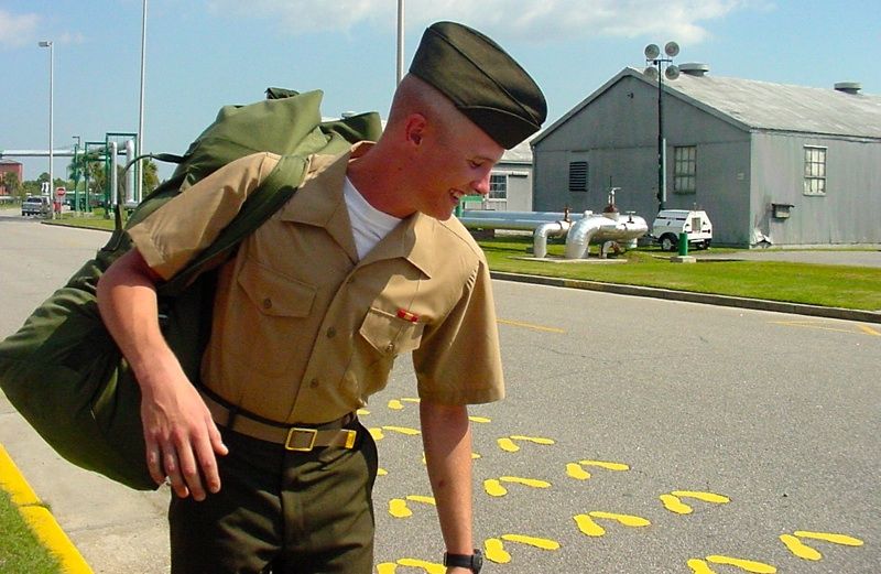 A smiling soldier with a pack over his shoulder