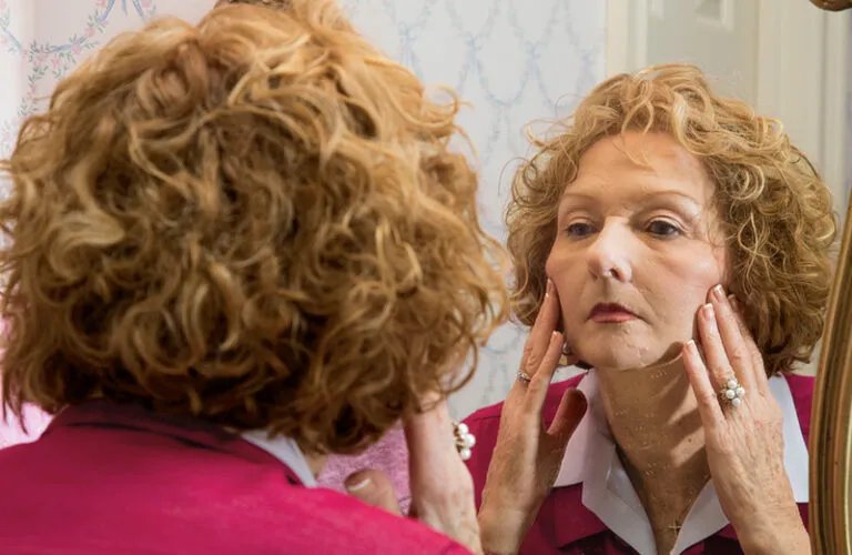 Marion Bond West examines her face in a mirror.