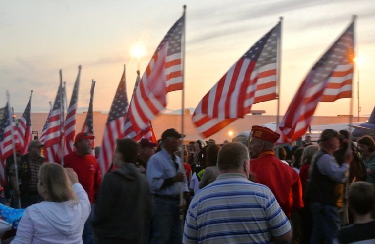 Waving flags and cheering people welcoming home an Honor Flight