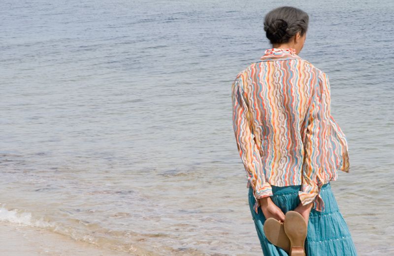 A woman walks along the beach, deep in thought.