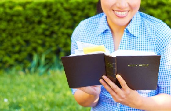 woman smiling while reading the Bible