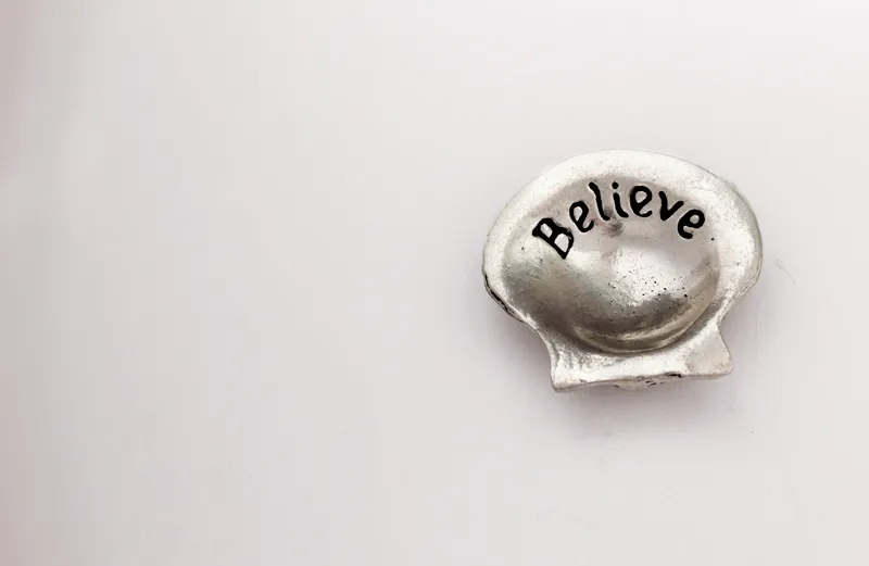 The word 'believe' inscribed on a seashell