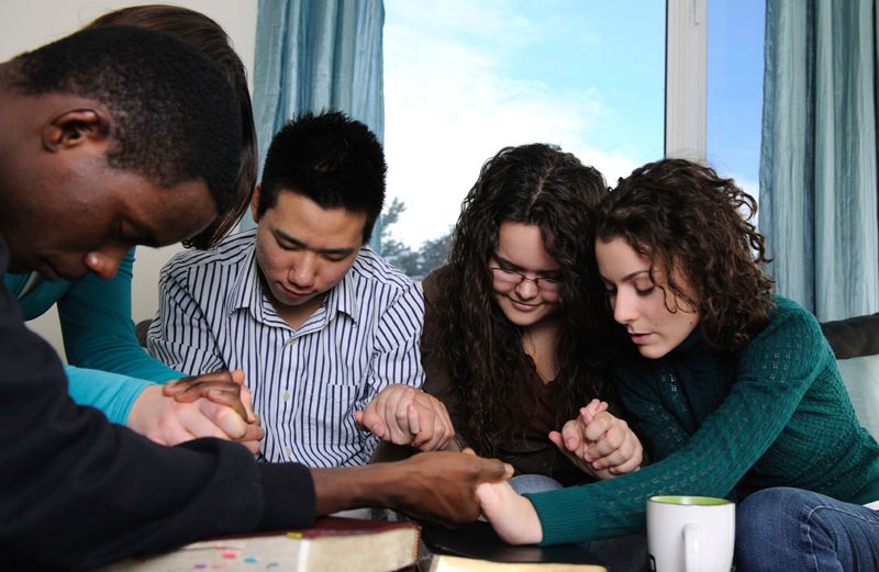 A circle of friends gather in prayer.