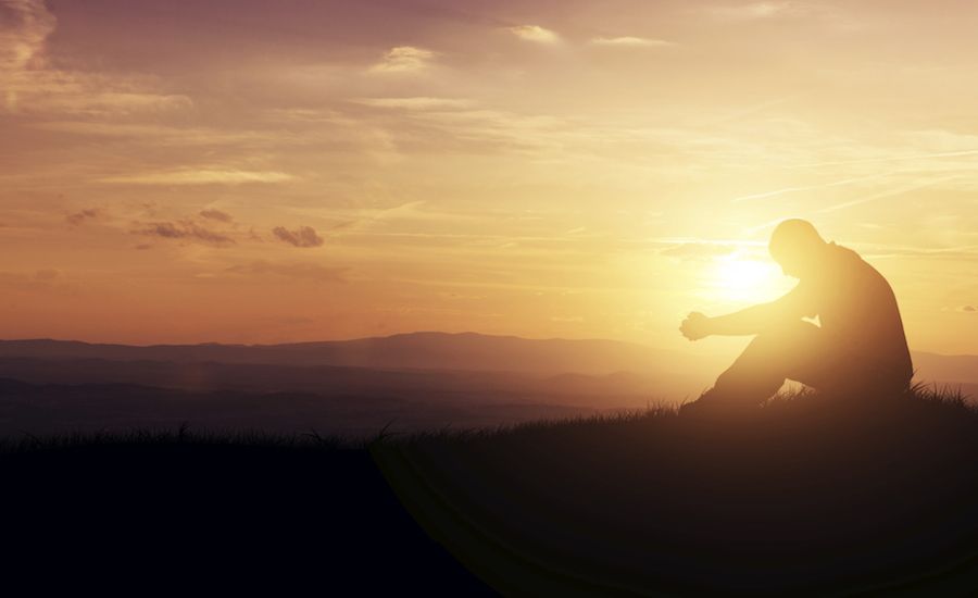 Man praying at sunrise.