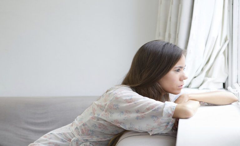 a woman looks out of a window wondering why God allows bad things to happen