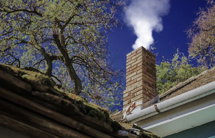 Guideposts: Wood smoke wafts skyward from the chimney of a suburban home.