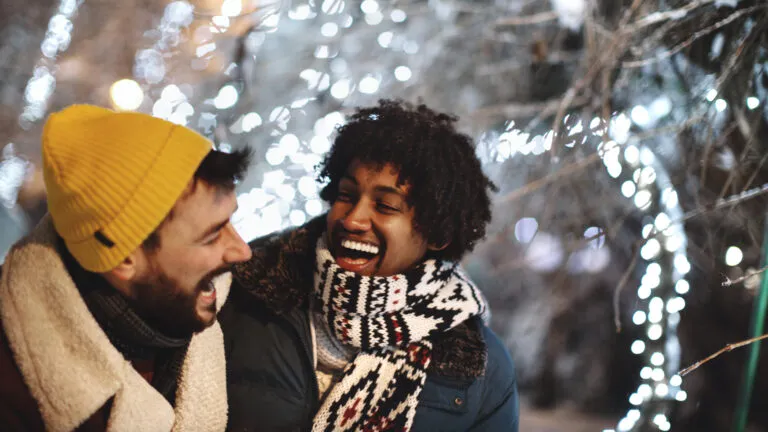 Two friends laughing outside in winter and saying a new year prayer for friends