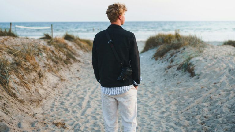 Man walking on beach sand during the day.