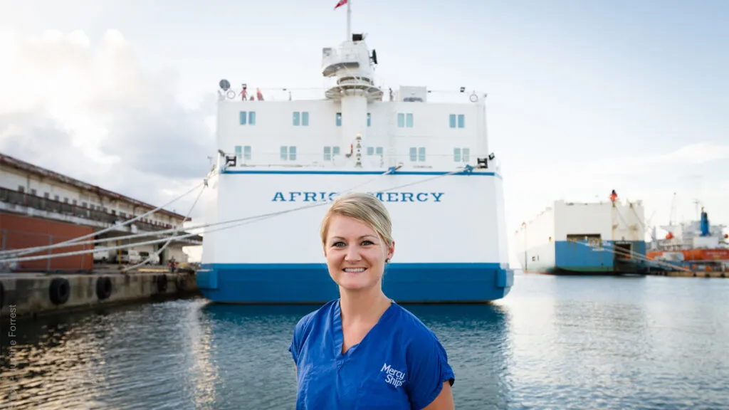 Heather Morehouse poses in front of the ship she served on, Africa Mercy