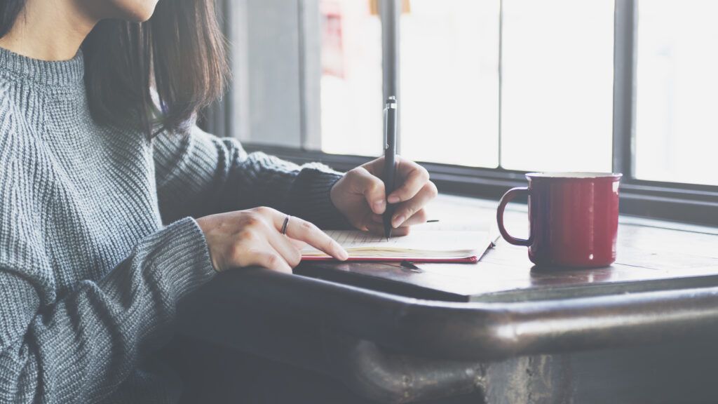 a woman writes in a journal