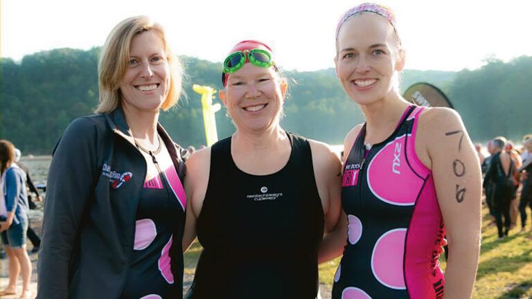 Millie and two friends smile after taking part in a triathlon