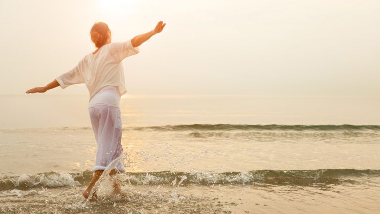 a woman walks on the beach happy and positive