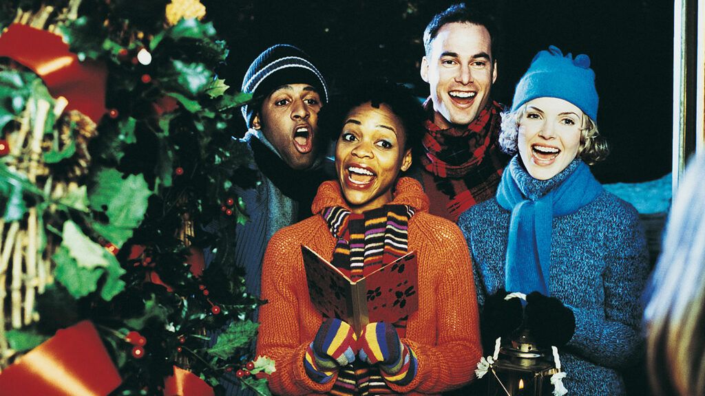 A quartet of carolers sing at the front door of a residence