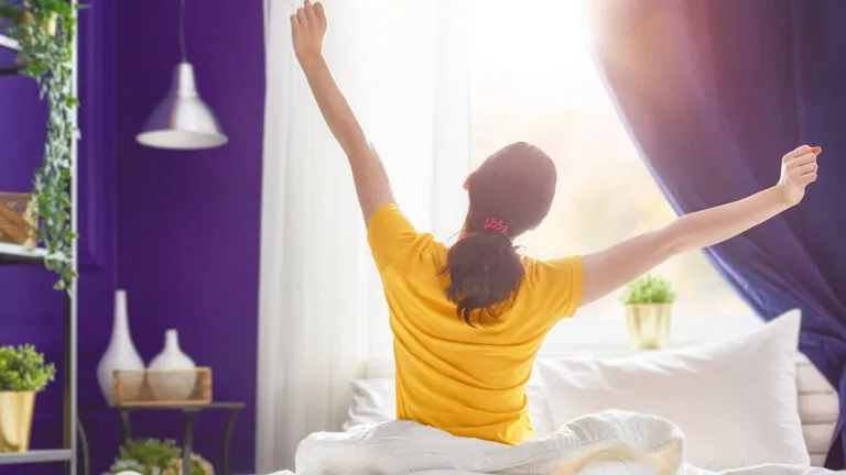 A woman stretches her arms as she awakens to a sunny day