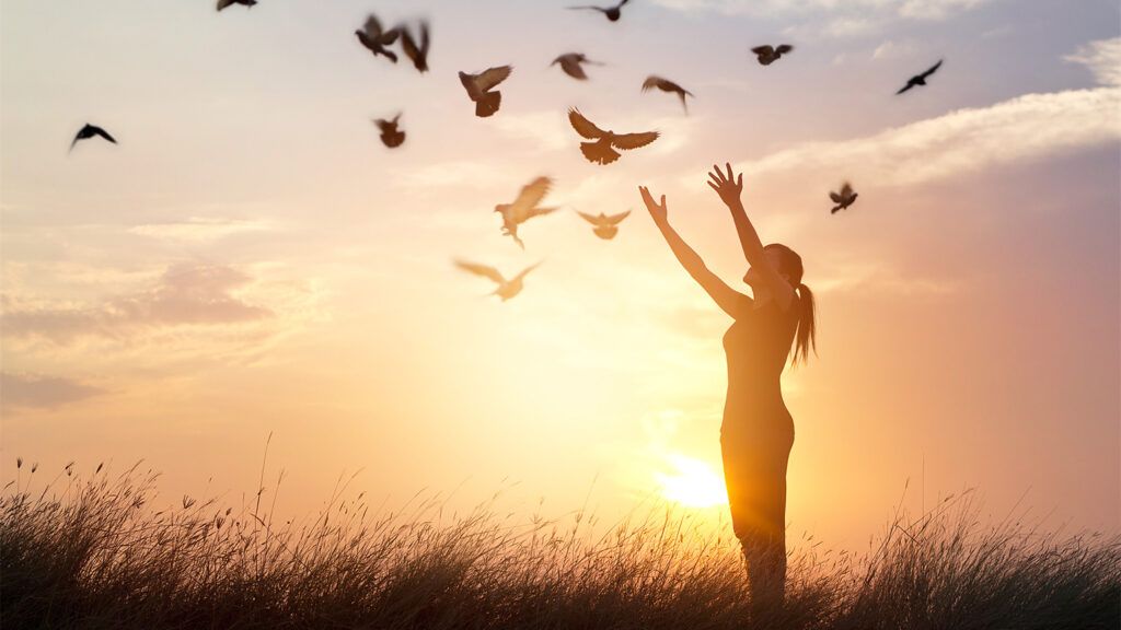 A woman releases a dove at sunrise