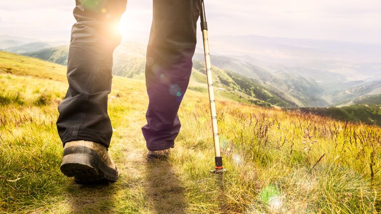 Man's feet hiking through a sun-drenched field