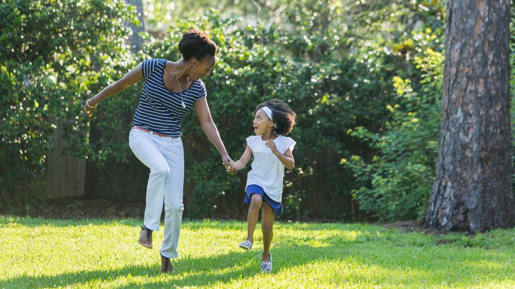 A mother and daughter frolic outside on a sunny day