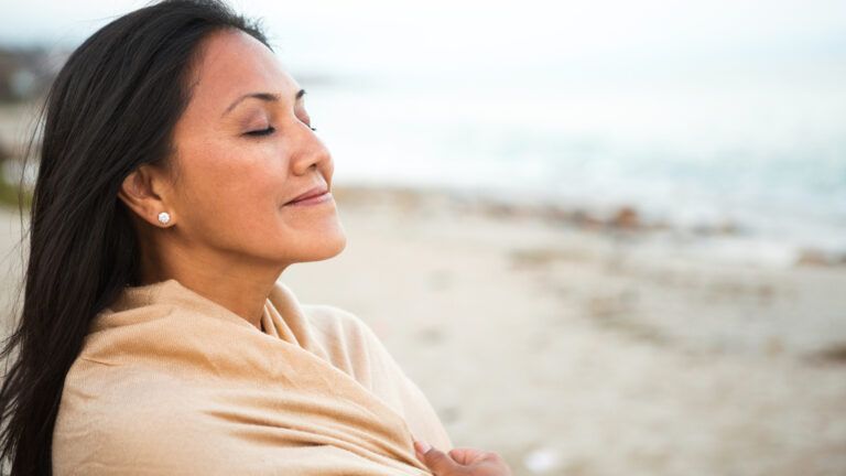 Woman praying for others on the beach during her ash wednesday reflection