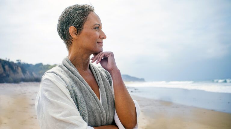 A contented woman gazes thoughtfully out at the ocean