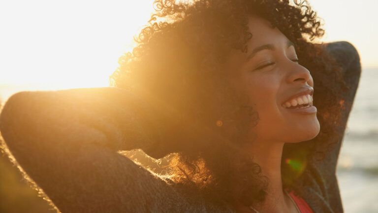 A young woman smiles contentedly on a bright sunny day