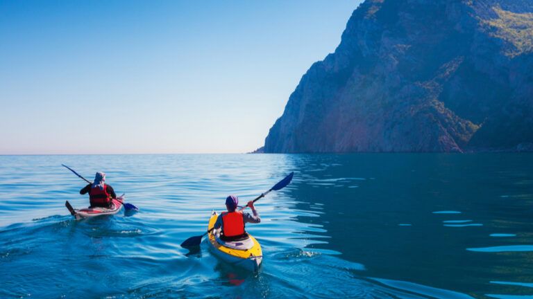 Two kayakers on the water saying prayers for safe travel