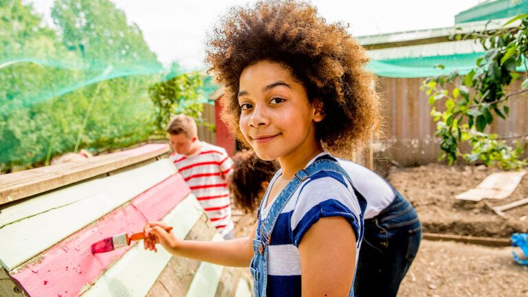 A young girl helps a home renovation charity with painting