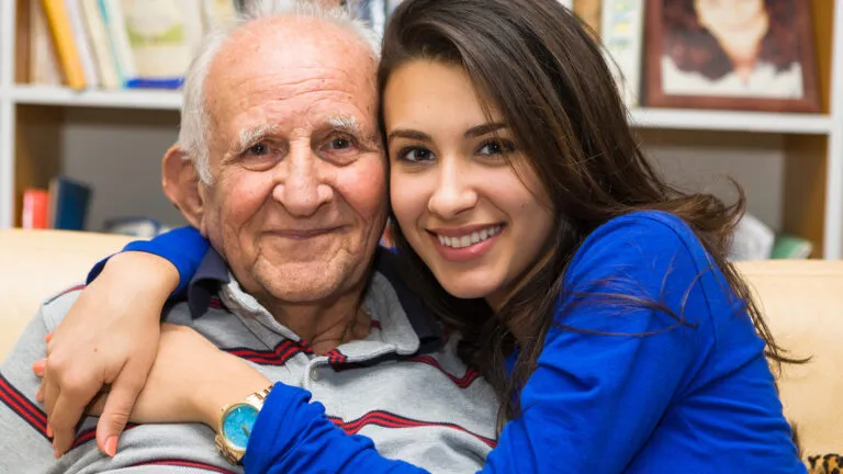 Elderly eighty plus year old man with granddaughter in a home setting.