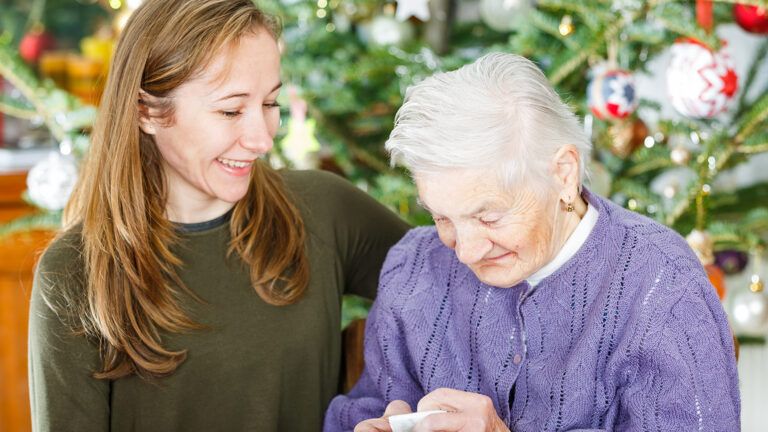 A young woman visits a senior woman at Christmastime