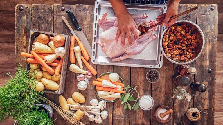 An overhead shot of a woman's hands stuffing a turkey