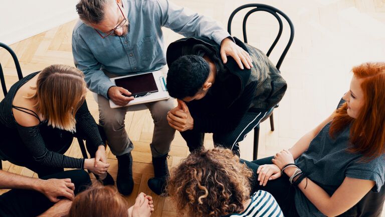 A young man is comforted in a group counseling session