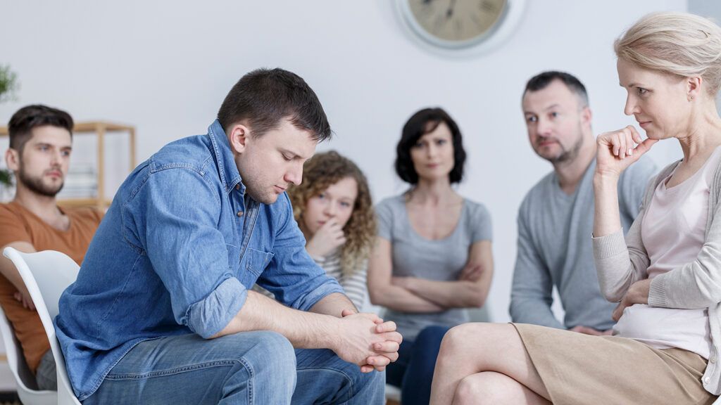 A young man struggles during a recovery support group session