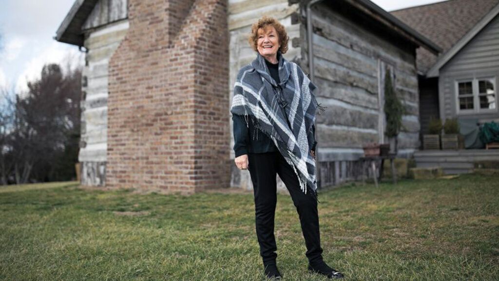 Ginny Curry smiling in front of her Christmas cabin.