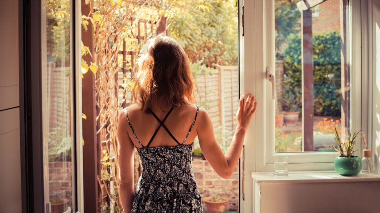 A young woman gazes out the doorway of her home