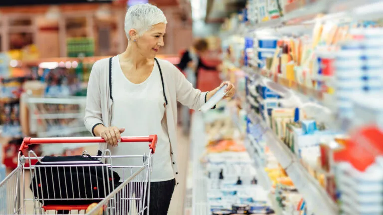 An older woman grocery shopping on a budget.