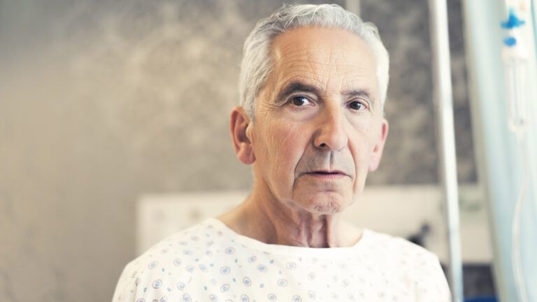 A headshot of a man in a hospital gown.