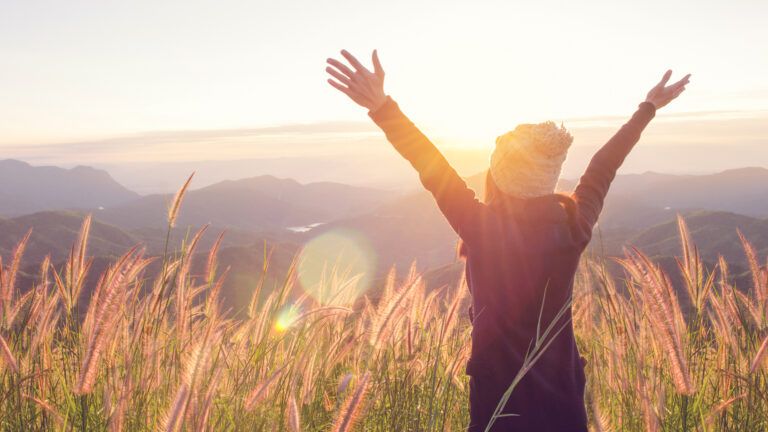 A girl in nature, arms in the air.