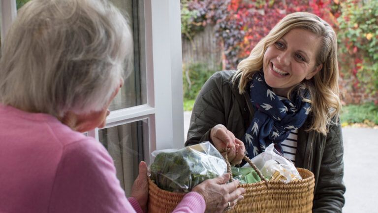 Woman helping senior woman with groceries